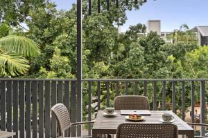 ヌーサヘッズにあるFrench Quarter by Stay Noosaのテーブルと椅子、バルコニー(ノートパソコン付)