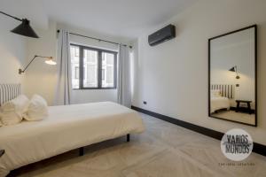 ein Schlafzimmer mit einem großen weißen Bett und einem Spiegel in der Unterkunft Un Madrid histórico para 4, en Plaza del Carmen E2 in Madrid