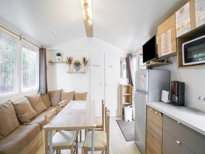 Una cocina y una sala de estar con un sofá y una mesa. en Swanky Mobile Home in Saint Jean de Monts near Seabeach, en Saint-Jean-de-Monts