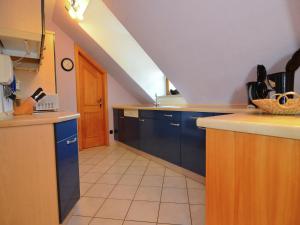 a large kitchen with blue cabinets and a staircase at Homely Apartment in Riedenburg Prunn near Forest with BBQ in Riedenburg