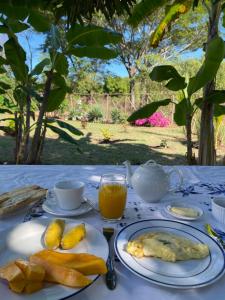 a table with plates of food and cups of orange juice at Le petit relais 2 in Nosy Be