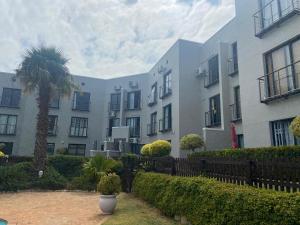 a building with a palm tree in front of it at Modern Sea and Mountain View Apartment - Gordon's Bay in Gordonʼs Bay