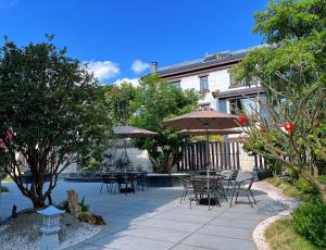 a patio with tables and chairs and an umbrella at Pu'er Jianquan Tea Rhythm Xianglan Smart Private Hot Spring Courtyard Resort B&B in Pu'er