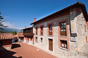 un gran edificio de piedra con ventanas y balcón en Apartamentos el Cueto de los Collado, en Villanueva de Pría