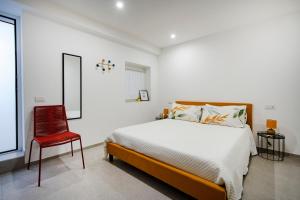 ein Schlafzimmer mit einem Bett und einem roten Stuhl in der Unterkunft Dimora dei Colori - Yellow Light in Bari