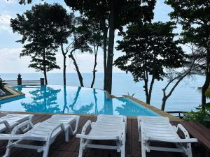a swimming pool with white chairs and the ocean at Chang Cliff Resort in Ko Chang