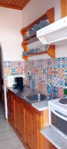 a kitchen with a sink and a tile wall at Villa Makis Studios in Skiathos Town +30 photos