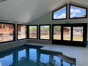 a swimming pool in a house with windows at L'Ecrin des Myrtilles - Appartement cosy - Piscine et vue montagne - Alpes - Val d'Arly - Aravis et Beaufortain in Flumet