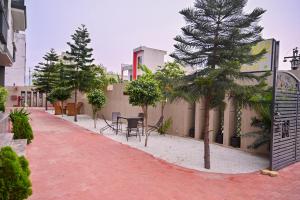 Una pasarela de ladrillos rojos con una mesa, sillas y árboles. en R K Hotel And Bar, en Pushkar