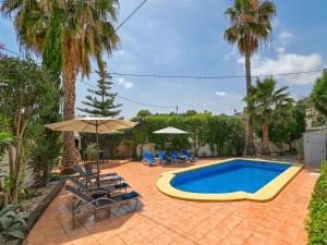 a pool with chairs and umbrellas in a yard at Elegant Villa with Pool in Benissa