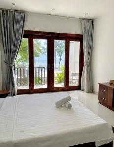 a bedroom with a large bed with a large window at RESORT HAVANA Mũi Né in Mui Ne