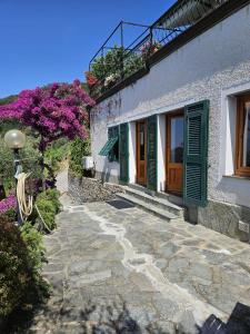 una casa con persianas verdes y una pasarela de piedra en Villa Onde e Ulivi, en San Bernardo