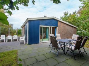内斯Holiday Home Ameland near North Sea Beach的天井上带桌椅的蓝色棚子