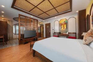 Un dormitorio con una cama blanca y un televisor de pantalla plana. en Veshia Hotel & Spa, en Hanói