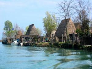 eine Gruppe von Hütten auf dem Wasser mit einem Boot in der Unterkunft Snug holiday home in Porto Santa Margherita with terrace in Porto Santa Margherita + 30 Fotos
