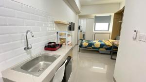 a kitchen with a sink and a bed in a room at Bandaraya Apartment Tallasa City 10B21 By Millpro in Pacinongong