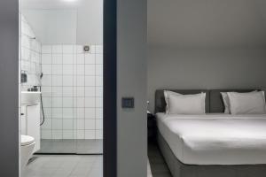 ein Schlafzimmer mit einem weißen Bett und ein Badezimmer in der Unterkunft Sapiens Hotel in Taschkent + 53 Fotos