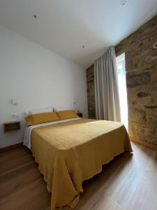 a bedroom with a large bed with yellow sheets and a window at A de Laura in Lariño