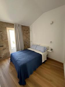 a bedroom with a large bed with a blue blanket at A de Laura in Lariño