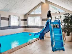a indoor swimming pool with a blue slide in a room at 18 person holiday home in Væggerløse in Marielyst