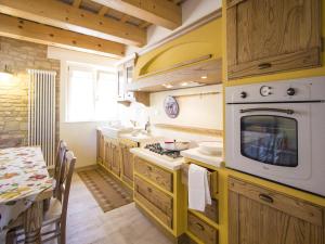 a kitchen with wooden cabinets and a table and a microwave at Belvilla by OYO Villa Vanessa Coccinella in Fano
