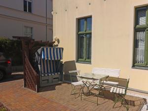 eine Terrasse mit Stühlen und einem Tisch und einem Gebäude in der Unterkunft Apartment sea noise, Ahlbeck in Ahlbeck
