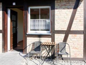 deux chaises et une table devant un bâtiment dans l'établissement Farmstay Neuendorfkrug, Lütow, à Lütow