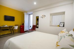 ein Schlafzimmer mit einem weißen Bett und einer gelben Wand in der Unterkunft Dimora dei Colori - Yellow Light in Bari