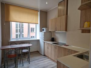 a kitchen with wooden cabinets and a table with chairs at Vienības 8-23 in Daugavpils