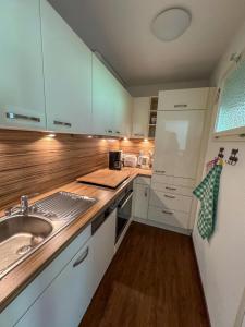 a kitchen with white cabinets and a sink at Allgäutraum in Bolsterlang