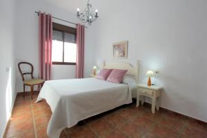 a white bedroom with a bed and a chair at Casa Rocio 1 in Conil de la Frontera +10 photos