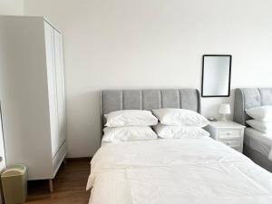 a white bedroom with a bed with white sheets and pillows at ICC Suites Ipoh 16th floor in Ipoh