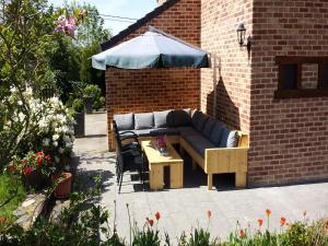 a couch and a table and an umbrella on a patio at Atmospheric holiday home in Durbuy with sauna in Septon