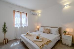 une chambre blanche avec un lit avec deux serviettes dessus dans l'établissement House Design nel Cuore di Porto Rotondo, à Porto Rotondo