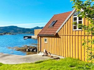 ein gelbes Gebäude mit einem roten Dach neben einem Gewässer in der Unterkunft 6 person holiday home in MÅLØY in Måløy + 30 Fotos