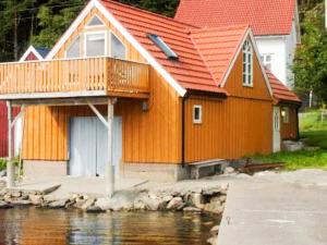 a house with an orange roof next to a body of water at 6 person holiday home in MÅLØY in Måløy