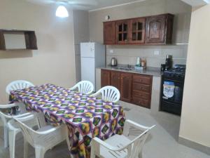 eine Küche mit einem Tisch und weißen Stühlen sowie eine Küche mit einem Herd in der Unterkunft Departamentos omill 154 in La Banda