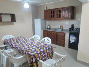 eine Küche mit einem Tisch und weißen Stühlen sowie eine Küche mit einem Herd in der Unterkunft Departamentos omill 154 in La Banda