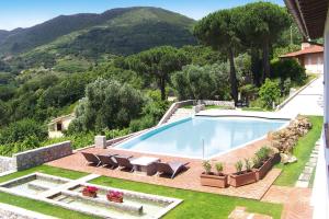 a swimming pool in a yard with chairs and a mountain at Residence La Chiusa di Rio, Rio nell'Elba in Rio nellʼElba