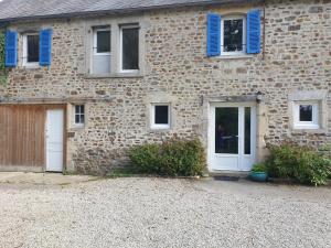 a brick house with blue shuttered windows and doors at Semi-detached house, St Sauveur-le-Vicomte in Saint-Sauveur-le-Vicomte