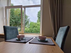 a dining room table with two chairs and a large window at Central Stay Appartments in Šiauliai +7 photos