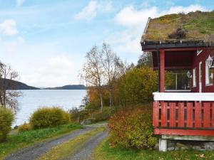 a red house on a road next to a body of water at 6 person holiday home in VATNE-By Traum in Vatne