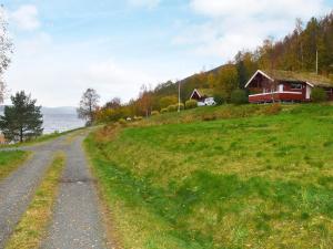 a dirt road next to a field with a house at 6 person holiday home in VATNE-By Traum in Vatne