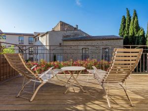 2 chaises et une table sur une terrasse avec un bâtiment dans l'établissement Garrigae Distillerie de Pezenas - Hotellerie & Spa, à Pézenas