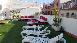 un patio con sillas blancas y mesas en el techo en Apartamentos Doña Lola en Sevilla