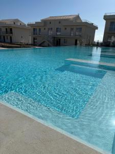 a large blue swimming pool with buildings in the background at Eco del Mare in Pachino