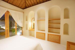 a bedroom with white walls and a bed and shelves at Aloha Boutique Uluwatu in Uluwatu