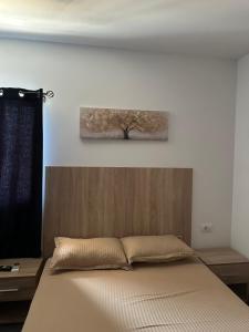 a bedroom with a bed with a tree painting on the wall at Casa Plaja Corbu in Corbu