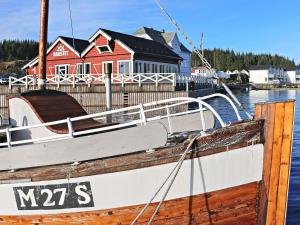 een boot is aangemeerd voor een rood huis bij 6 person holiday home in Austrheim in Utkeila
