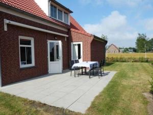 a patio with a table and chairs next to a brick building at Rural holiday home with terrace in Breskens